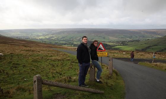 A person and person standing on a road
Description automatically generated